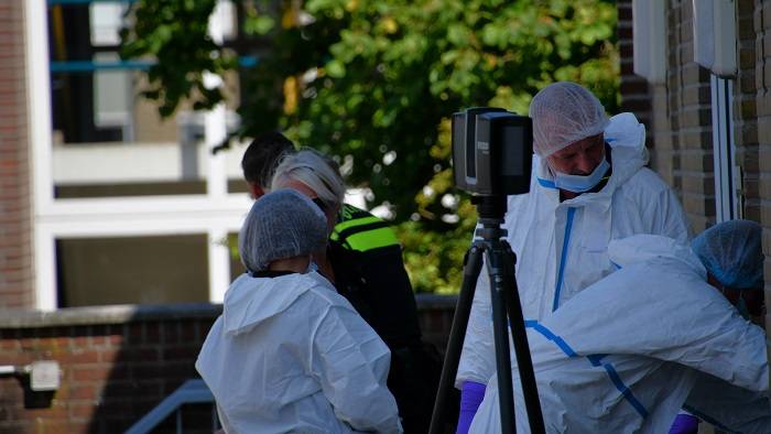 meerdere rechercheurs in witte pakken doen onderzoek