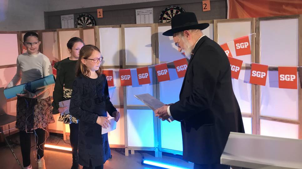 Opperrabbijn Binyomin Jacobs neemt tekeningen in ontvangst van schoolkinderen uit Reimerswaal en Kapelle.