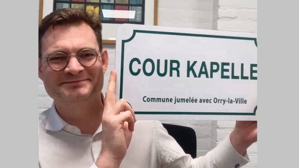 Burgemeester Jansen op de Haar met het straatbord 'Cour Kapelle'