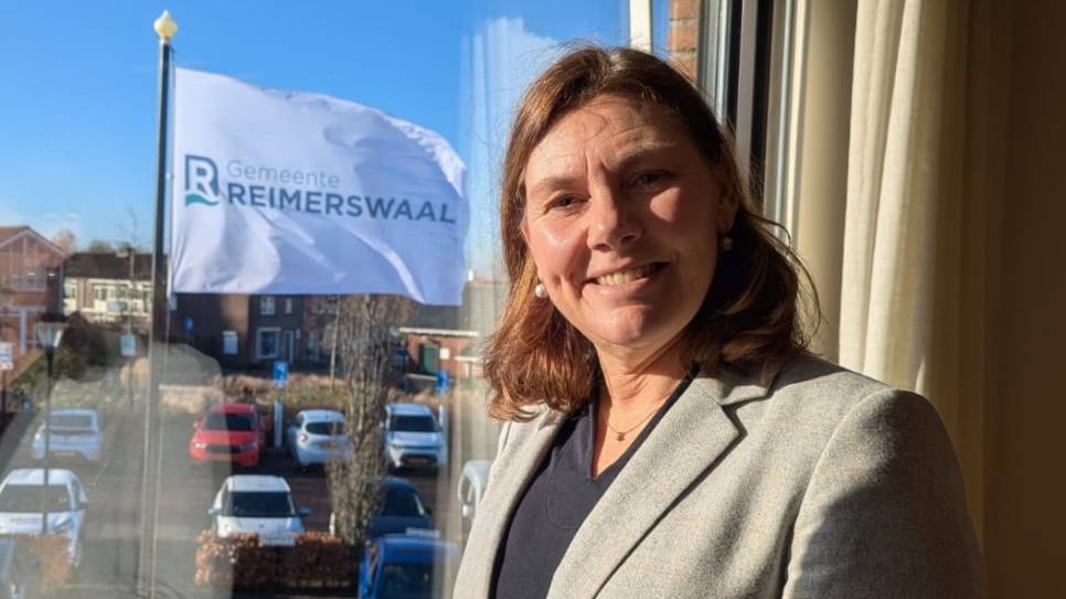 Burgemeester José van Egmond, voor de vlag met het nieuwe logo.