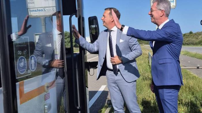 Wethouder Van Belzen (links) en gedeputeerde Harry van der Maas zwaaien de buschauffeur uit, bij de eerste rijronde.