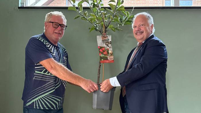 Nico Slaakweg uit Ovezande krijgt van wethouder Mackintosh (rechts op de foto) het fruitboompje.