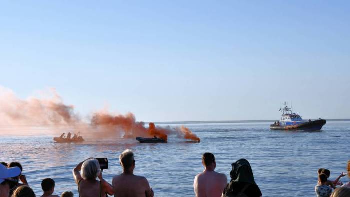 Toeschouwers kijken hoe de KNRM een 'reddingsactie' voor de kust uitvoert