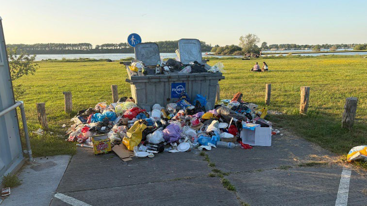 Vuilniszakken naast de afvalcontainer.