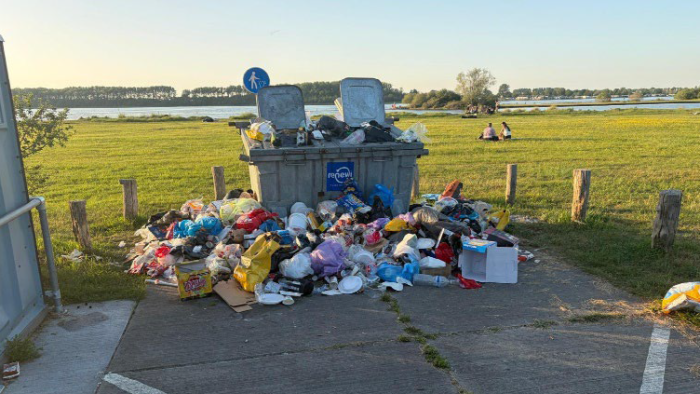 Vuilniszakken naast de afvalcontainer.