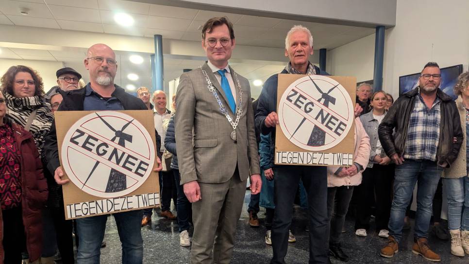 Burgemeester Constantijn Jansen op de Haar temidden van twee demonstraten met protestborden. Rechts naast hem, André Schrier.