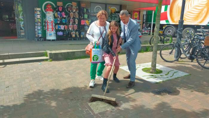 Joke Folmer, kinderburgemeester Claire van Moort en wethouder Jon Herselman (vlnr) onthullen de tegel in Wemeldinge.,