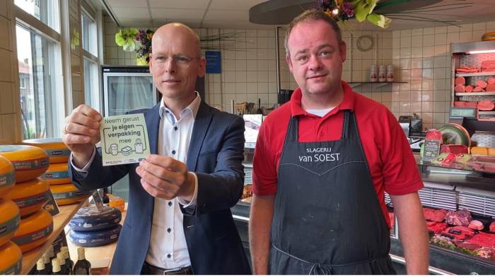 Slager Robbert van Soest (rechts) en wethouder Maarten Both die de nieuwe sticker toont.