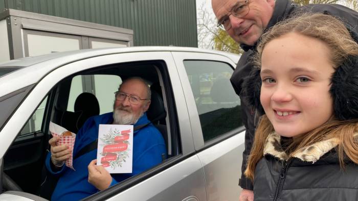 Kinderburgemeester Eva Griep en wethouder Ad Meeuwsen geven een automobilist kerstattenties mee.