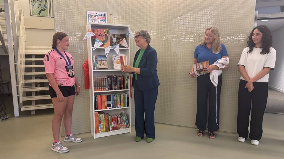 Wethouder Marga van de Plasse geeft het eerste boek uit de kast aan Eefke van Stee